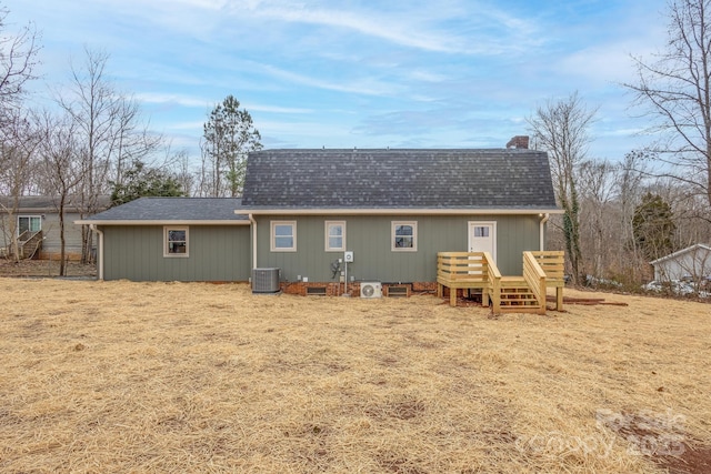 rear view of property with central AC unit and a lawn