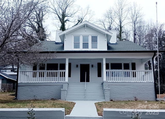 bungalow featuring a shingled roof, covered porch, and a chimney