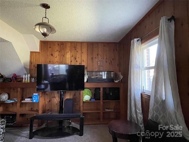 living room with wooden walls, a textured ceiling, and carpet