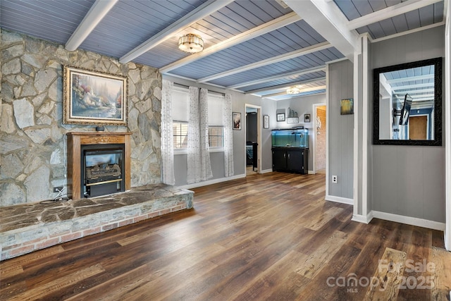 unfurnished living room with dark hardwood / wood-style floors, a stone fireplace, and beam ceiling