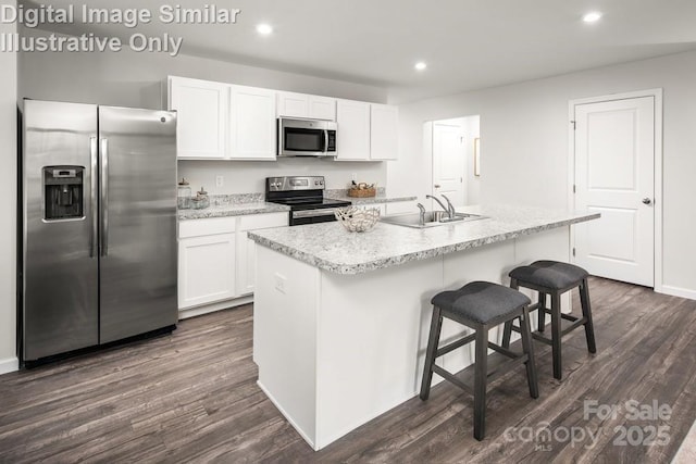 kitchen with an island with sink, sink, white cabinets, dark hardwood / wood-style flooring, and stainless steel appliances