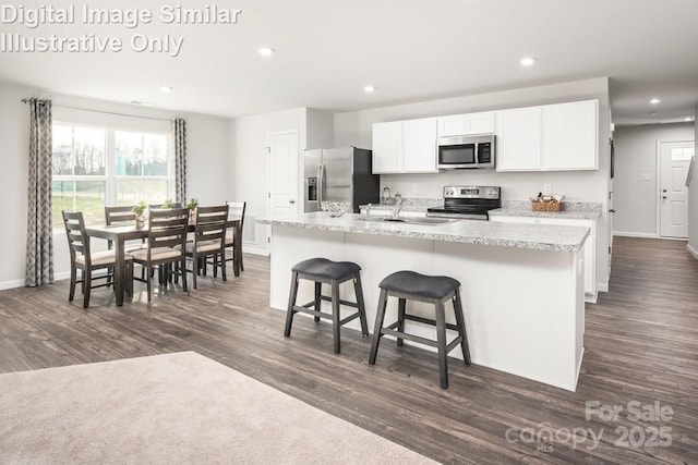 kitchen with sink, a breakfast bar area, appliances with stainless steel finishes, a kitchen island with sink, and white cabinets