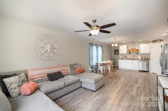 living room featuring sink, light hardwood / wood-style flooring, and ceiling fan