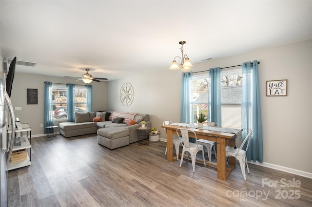 dining room with hardwood / wood-style flooring, plenty of natural light, and ceiling fan with notable chandelier