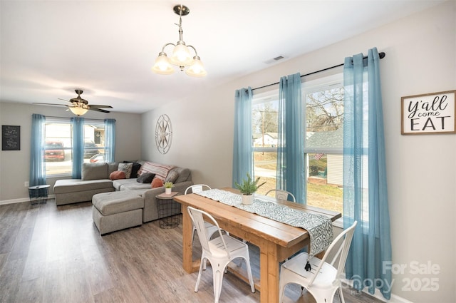 dining space with hardwood / wood-style flooring and ceiling fan with notable chandelier