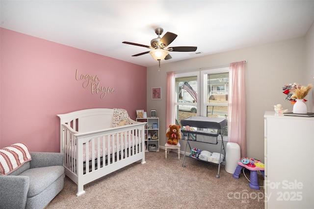 bedroom with carpet floors, a nursery area, and ceiling fan