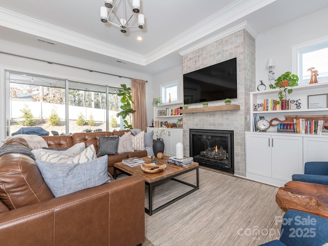 living room featuring an inviting chandelier, a fireplace, and ornamental molding