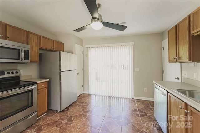 kitchen with ceiling fan, appliances with stainless steel finishes, sink, and dark tile patterned floors