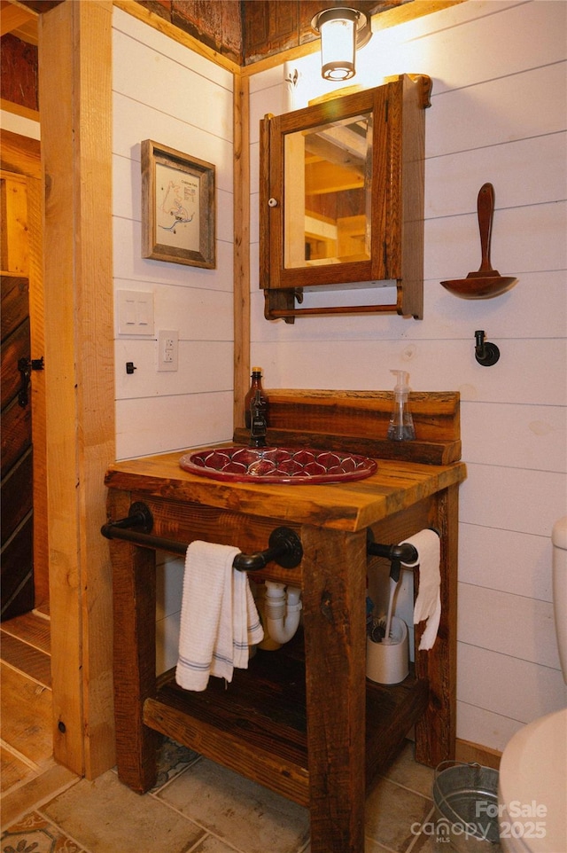 bathroom featuring wooden walls and toilet