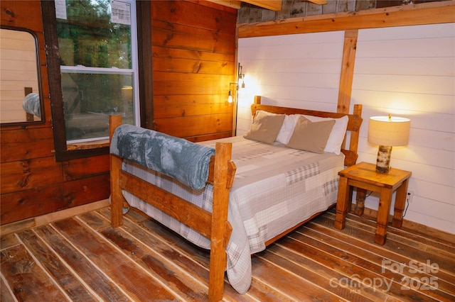 bedroom featuring dark wood-type flooring and wood walls