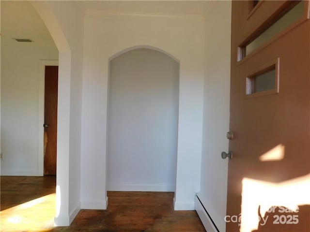 corridor featuring dark hardwood / wood-style flooring, crown molding, and baseboard heating