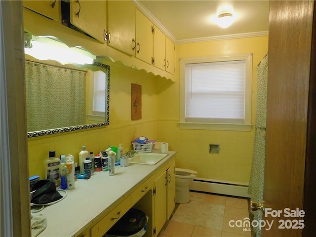 bathroom with toilet, crown molding, tile walls, tile patterned flooring, and a baseboard heating unit