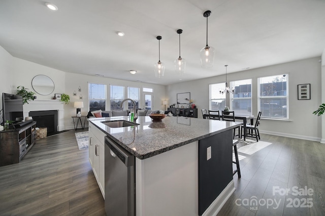 kitchen featuring white cabinetry, sink, stainless steel dishwasher, light stone countertops, and a center island with sink