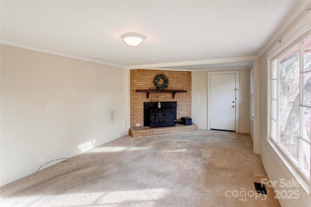 unfurnished living room featuring crown molding, a brick fireplace, and carpet