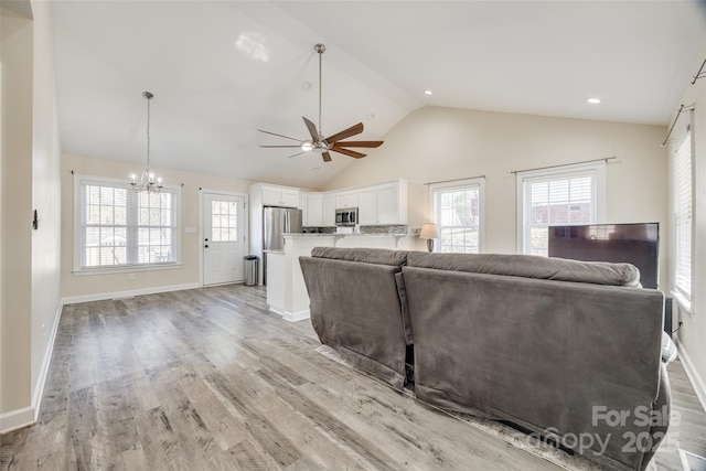 living room with vaulted ceiling, ceiling fan with notable chandelier, and light hardwood / wood-style floors