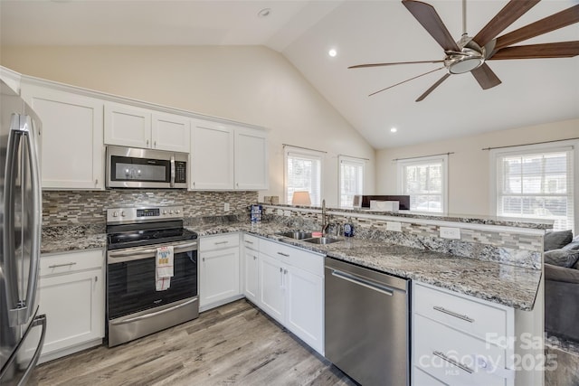 kitchen featuring appliances with stainless steel finishes, kitchen peninsula, sink, and white cabinets