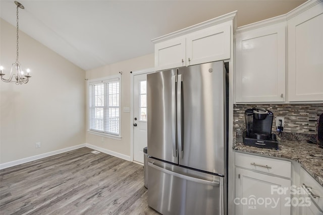 kitchen featuring white cabinetry, decorative backsplash, stainless steel fridge, and dark stone countertops