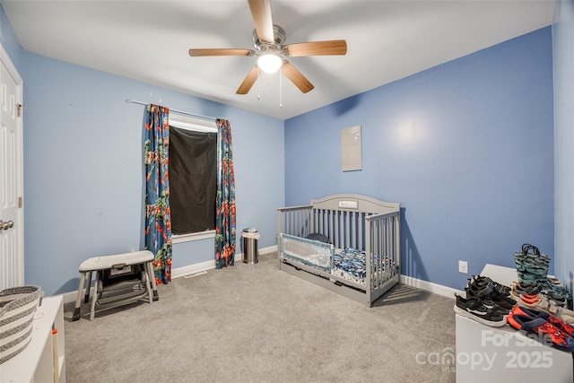 carpeted bedroom featuring a crib and ceiling fan