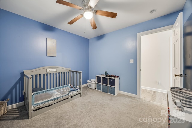 bedroom featuring a crib, carpet floors, and ceiling fan