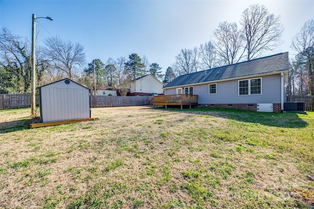 view of yard with central AC, a deck, and a storage unit