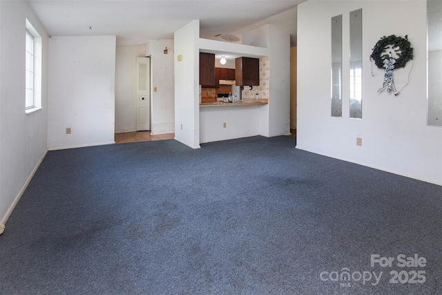 unfurnished living room featuring lofted ceiling and dark carpet