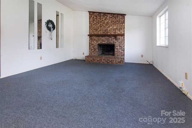 unfurnished living room with lofted ceiling, a fireplace, and dark carpet