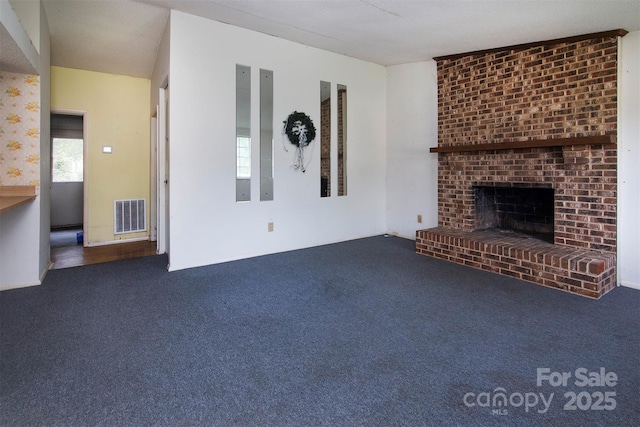 unfurnished living room with a brick fireplace and dark colored carpet