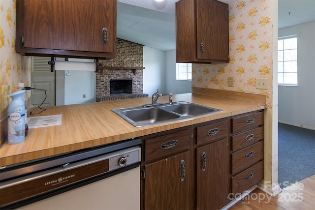 kitchen featuring vaulted ceiling, kitchen peninsula, sink, dark brown cabinetry, and white dishwasher