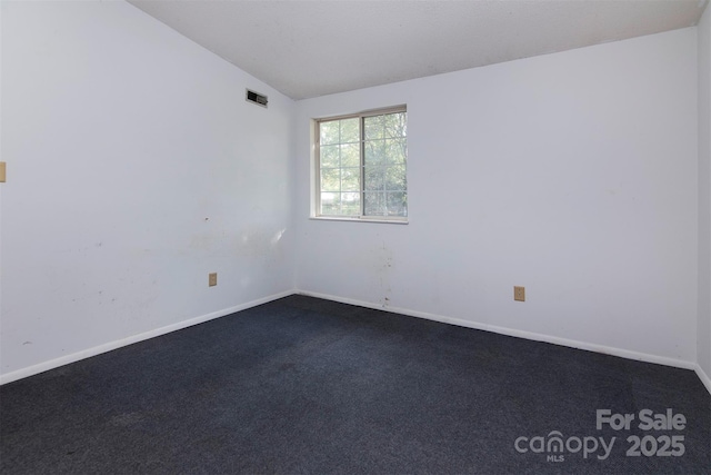 spare room with dark carpet and vaulted ceiling