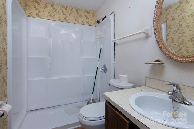 bathroom with vanity, toilet, and a shower