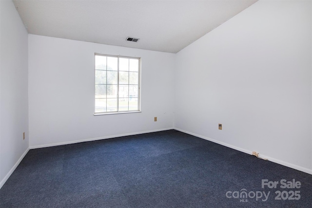 carpeted empty room featuring vaulted ceiling