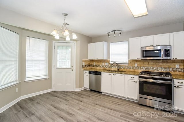 kitchen with white cabinetry, appliances with stainless steel finishes, sink, and pendant lighting