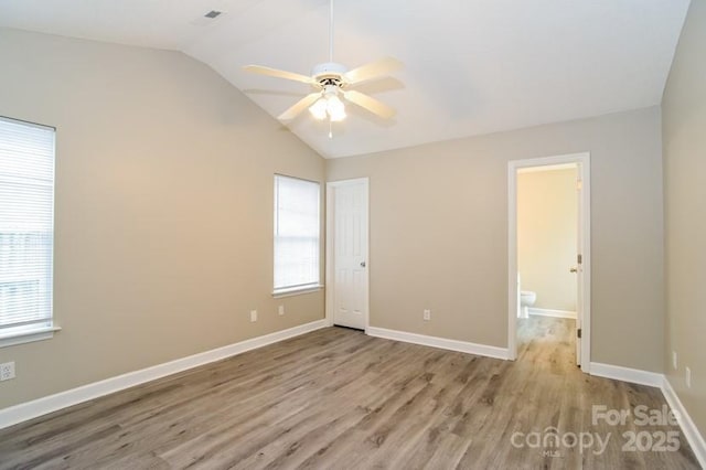 unfurnished bedroom featuring vaulted ceiling, ensuite bathroom, ceiling fan, and light hardwood / wood-style floors