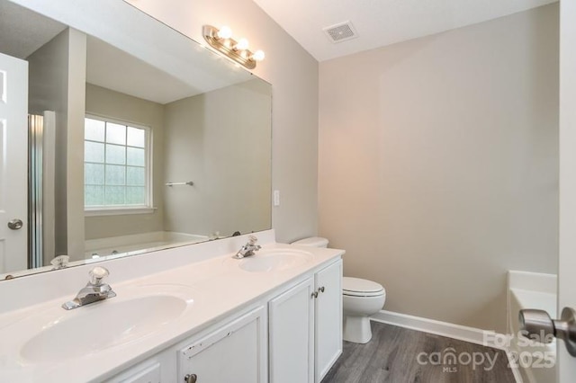 bathroom with a washtub, vanity, hardwood / wood-style flooring, and toilet