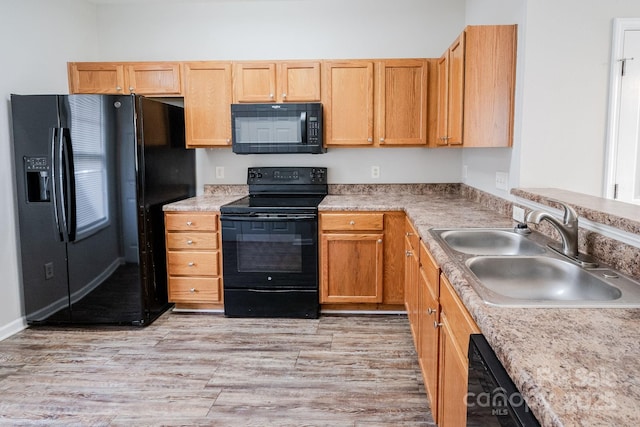 kitchen with sink, black appliances, and light hardwood / wood-style floors