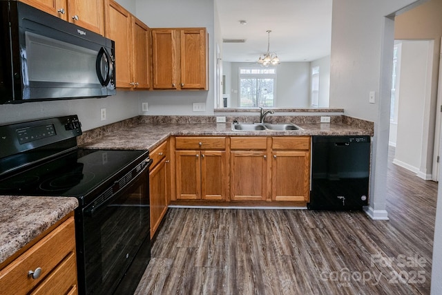 kitchen with pendant lighting, sink, dark hardwood / wood-style floors, black appliances, and kitchen peninsula