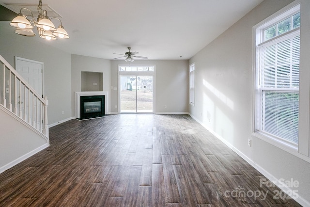 unfurnished living room with dark hardwood / wood-style flooring and ceiling fan with notable chandelier