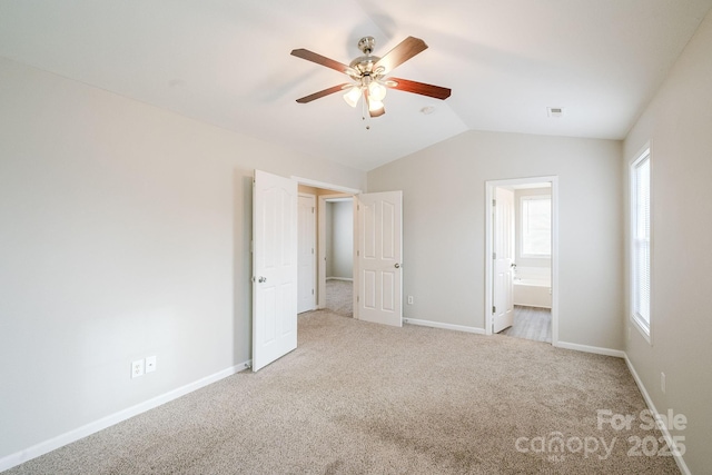 unfurnished bedroom with ceiling fan, ensuite bath, lofted ceiling, and light carpet