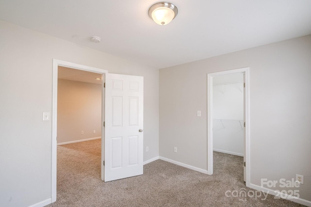 unfurnished bedroom featuring a spacious closet, light carpet, and a closet