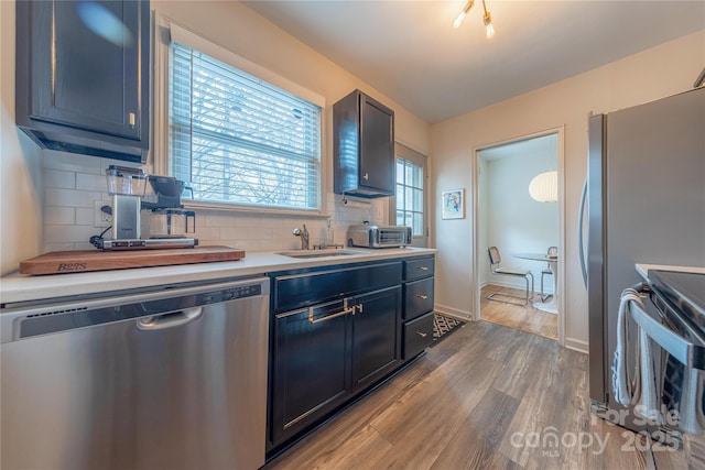 kitchen with sink, hardwood / wood-style flooring, dishwasher, tasteful backsplash, and range with electric stovetop