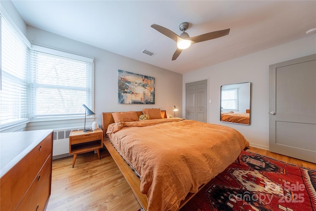 bedroom with ceiling fan, radiator, and light hardwood / wood-style flooring