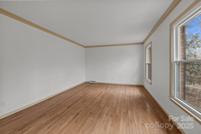 spare room with hardwood / wood-style floors, crown molding, and plenty of natural light