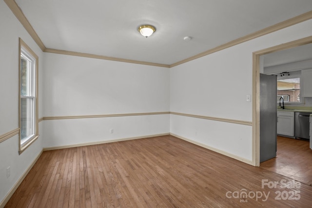 empty room with ornamental molding, sink, and light wood-type flooring