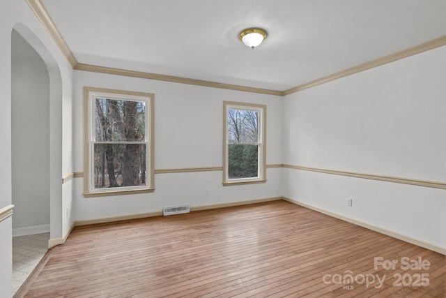 spare room with ornamental molding and light wood-type flooring