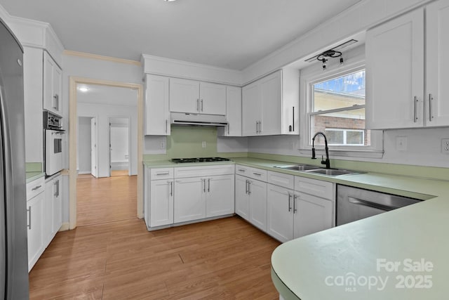 kitchen featuring sink, white cabinetry, light hardwood / wood-style flooring, ornamental molding, and appliances with stainless steel finishes