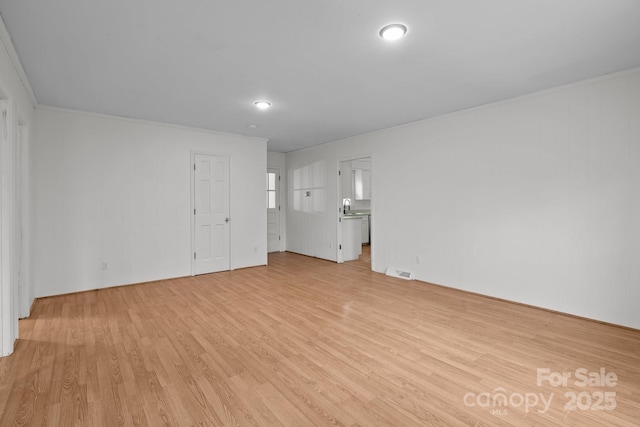 unfurnished living room featuring light hardwood / wood-style flooring and ornamental molding