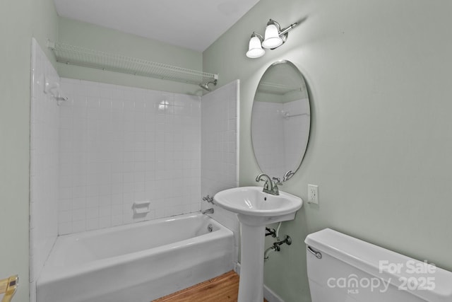 bathroom with tiled shower / bath combo, toilet, and hardwood / wood-style flooring