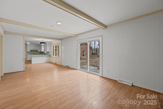 unfurnished living room featuring beam ceiling and light hardwood / wood-style flooring