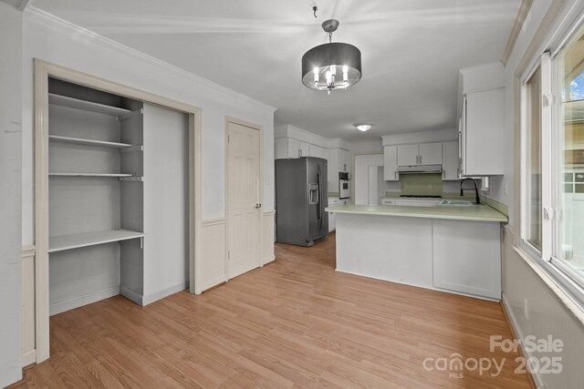 kitchen featuring pendant lighting, light hardwood / wood-style floors, white cabinets, black refrigerator with ice dispenser, and kitchen peninsula