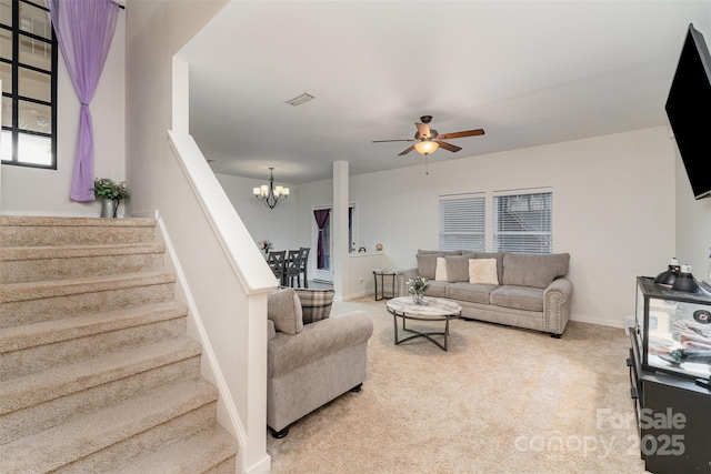 living room featuring ceiling fan with notable chandelier and carpet